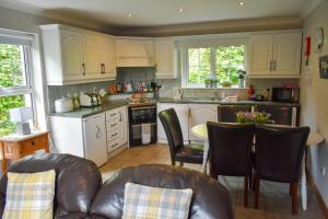 a kitchen with white cabinets and a table and chairs at Simply Donegal Adrihidbeg Cottage in Dungloe