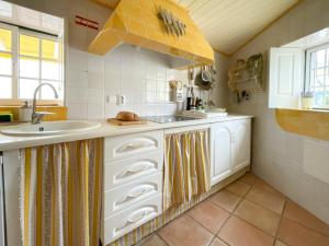 uma cozinha com armários brancos e um lavatório em Charming Countryside Home with Fireplace & Patio em Alcoutim