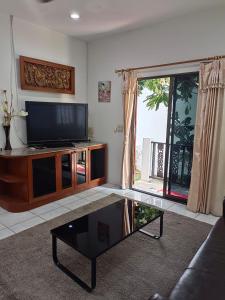 uma sala de estar com uma televisão de ecrã plano e uma mesa de centro em Kotchaphorn Garden em South Pattaya