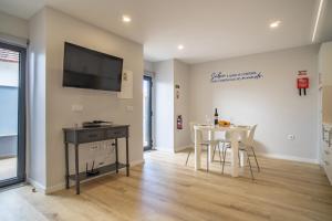 Ouri in Blue House في جارديم دو مار: غرفة معيشة مع طاولة وتلفزيون على الحائط