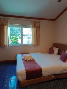 um quarto com uma cama grande em frente a uma janela em Kotchaphorn Garden em South Pattaya