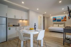 Ouri in Blue House في جارديم دو مار: مطبخ وغرفة معيشة مع طاولة وكراسي بيضاء