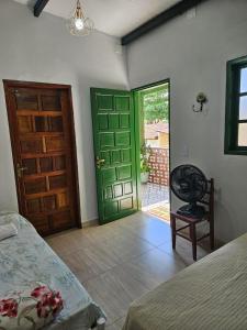 1 dormitorio con puerta verde, cama y silla en Suítes Pirenópolis, en Pirenópolis