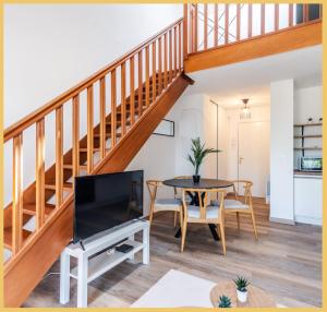 a living room with a staircase and a table with a tv at Appartement T2 Moderne Neuf Collonge in Collonges-sous-Salève