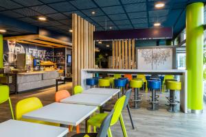 a restaurant with white tables and colorful chairs at ibis budget Paris Porte de Pantin in Pantin