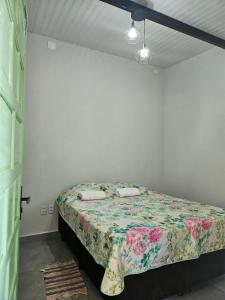 1 dormitorio con 1 cama con colcha de flores en Suítes Pirenópolis, en Pirenópolis