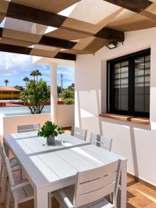 Laguna Home by Best Holidays Fuerteventura في كوراليخو: طاولة بيضاء وكراسي على فناء مع نافذة
