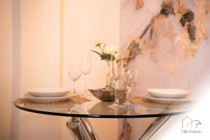 a glass table with wine glasses and plates on it at Belrado Apartments in Belgrade