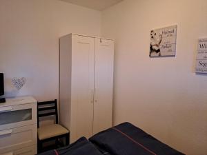 1 dormitorio con armario blanco y silla en Tanjasfewo - b42582 en Dornum
