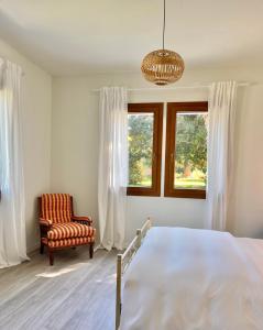 a bedroom with a bed and a chair and a chandelier at Agriturismo Borgo Rurale San Salvador-Casa del Maestro in Torre di Mosto