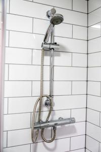 a shower head in a bathroom with white tiles at The Bark House by Night Stay in Birmingham