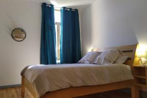 Schlafzimmer mit einem Bett mit blauen Vorhängen und einem Fenster in der Unterkunft Chartreuse in Saint-Franc
