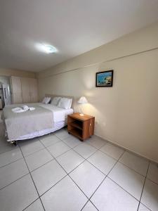 1 dormitorio con 1 cama y 1 mesa con lámpara en Terrazzo Ponta Negra Flat, en Natal
