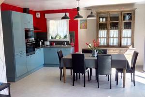 cocina con armarios azules, mesa y sillas en Ty Tiegezh Gîte TiDastum, en Créhen