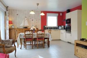 una cucina con tavolo, sedie e pareti rosse di Ty Tiegezh Gite Balafenn a Créhen