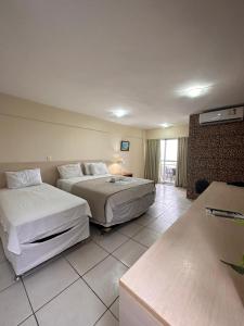 a hotel room with two beds and a window at Terrazzo Ponta Negra Flat in Natal
