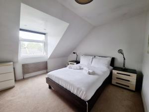 a bedroom with a bed with white sheets and a window at Bright top floor, 1 bed apartment in great location in London