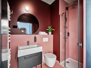 Łazienka z czerwonymi ścianami, umywalką i lustrem w obiekcie Basecamp Wroclaw we Wrocławiu