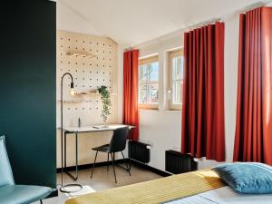 sypialnia z czerwonymi zasłonami, biurkiem i łóżkiem w obiekcie Basecamp Wroclaw we Wrocławiu