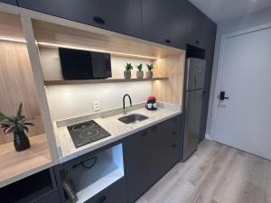 a small kitchen with a sink and a microwave at Loft no Bairro Auxiliadora in Porto Alegre