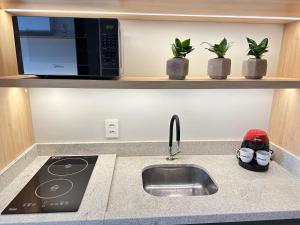 a kitchen counter with a sink and a microwave at Loft no Bairro Auxiliadora in Porto Alegre