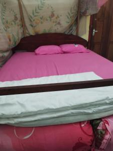 a bed with pink and white sheets on it at Agus Family Homestay in Labuan Bajo