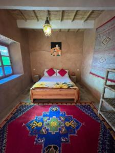 a bedroom with a bed with a rug on the floor at Riad Auberge Bassou in Nkob