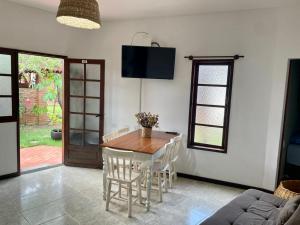 uma sala de jantar com uma mesa de madeira e cadeiras em Bangalô Amarelo em Prado