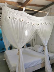 a white canopy bed with white drapes in a room at Gîte 1001 Nuits - SINBAD in Bouillante