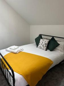 Una cama con manta amarilla y almohadas. en Quirky getaway @ The Old Bakery en Bristol