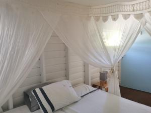a bedroom with a canopy bed with white curtains at Gîte 1001 Nuits - SINBAD in Bouillante