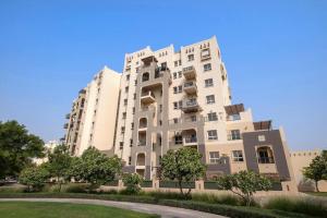 a tall white building with a lawn in front of it at Chic Studio with a Bath Tub, Pool & Gym near Golf Club in Dubai