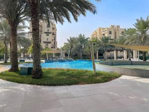 a swimming pool with palm trees and buildings at Chic Studio with a Bath Tub, Pool & Gym near Golf Club in Dubai