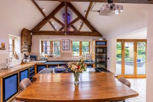 una cocina con una mesa de madera y un jarrón de flores en Blackgreaves Farmhouse, en Lea Marston