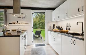Gorgeous Home In Hadsund With Wifi في Hadsund: مطبخ فيه دواليب بيضاء وباب يودي لساحة