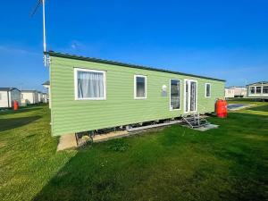 a green tiny house on a grass field at Lovely 8 Berth Caravan Nearby Scratby Beach In Norfolk Ref 50021f in Great Yarmouth