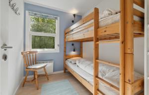 3 Bedroom Cozy Home In Aakirkeby في Vester Sømarken: غرفة نوم مع أسرة بطابقين وكرسي ونافذة