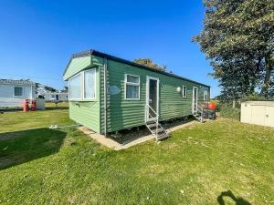 a green tiny house sitting in a yard at Brilliant 10 Berth Caravan At Valley Farm Holiday Park, Essex Ref 46443v in Great Clacton