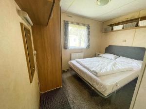 Great Clacton的住宿－Brilliant 10 Berth Caravan At Valley Farm Holiday Park, Essex Ref 46443v，一间小房间的卧室,配有一张床铺