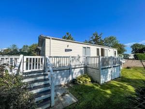 a small white house with a white fence at Beautiful Caravan With Decking At Carlton Meres Holiday Park, Suffolk Ref 60001m in Saxmundham
