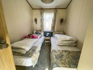een kamer met drie bedden in een kamer bij Beautiful Caravan With Decking At Carlton Meres Holiday Park, Suffolk Ref 60001m in Saxmundham