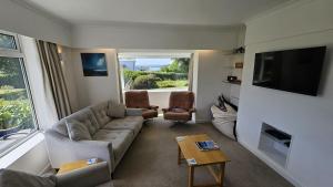 ein Wohnzimmer mit einem Sofa, Stühlen und einem TV in der Unterkunft Heathfield in Saint Mawes