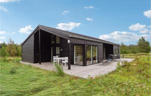 a black house with a deck in a field at Cozy Home In Fjerritslev With Kitchen in Slettestrand