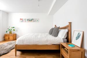 a bedroom with a wooden bed with white sheets and pillows at My City Spaces (Battersea) in London