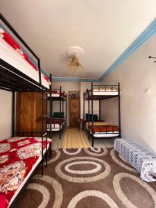 a room with three bunk beds and a carpet at Binic guest house in Taghazout