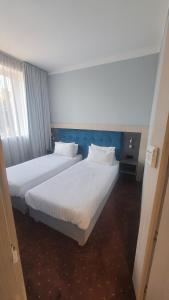 two beds in a hotel room with white sheets at euroHOTEL Sosnowiec Kazimierz in Sosnowiec