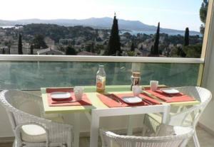 d'une table et de chaises blanches sur un balcon avec vue. dans l'établissement Hauts de Portissol 50 m2 terrasse 12 m2 Vue mer, à Sanary-sur-Mer
