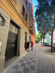 two people standing outside of a building on a street at Hostel Jasmin in Prague