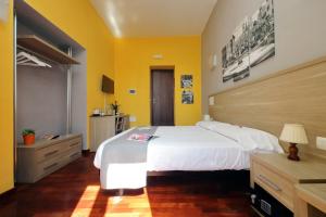 a bedroom with a large white bed and yellow walls at LHG Comfy Rooms in Rome