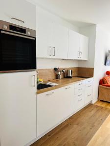 una cucina con armadi bianchi e un apparecchio nero di Hubertus Terrace&Garden Apartment a Garmisch-Partenkirchen